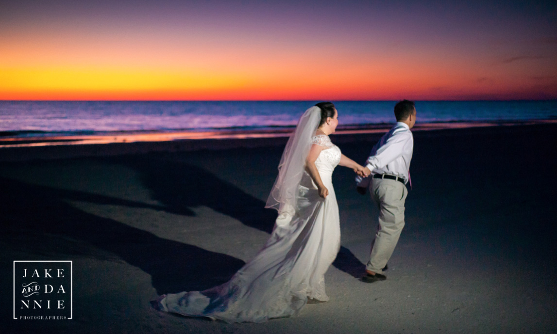 Bride and groom run across the sand in front of a beautiful flroida sunset in St. Petersburg