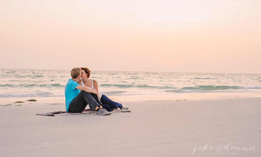 A couple sits in the sand while the waves crash in the background on this florida beach