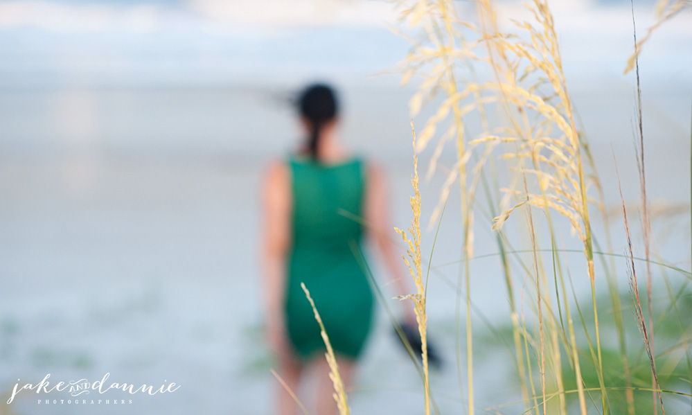 A photo of the grass by the beach with Dannie walking toward the ocean in the background
