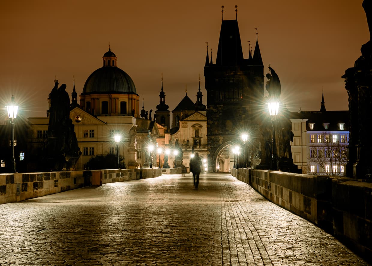 A single person walking on the Charles bridge in Prague.