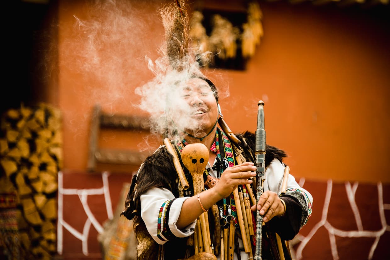 A performer smoking a traditional pipe in the Yunnan Ethnic Village.