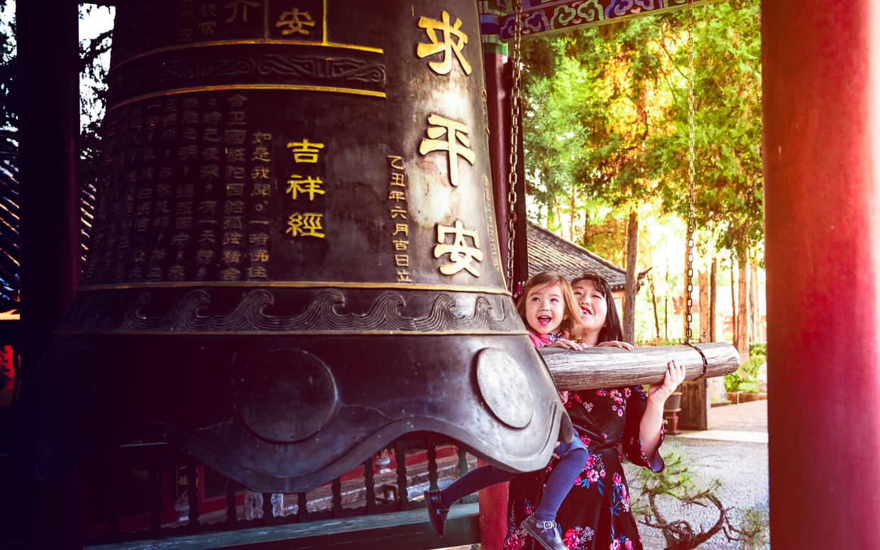 Striking the giant bell on top of Lion Hill in Lijiang.