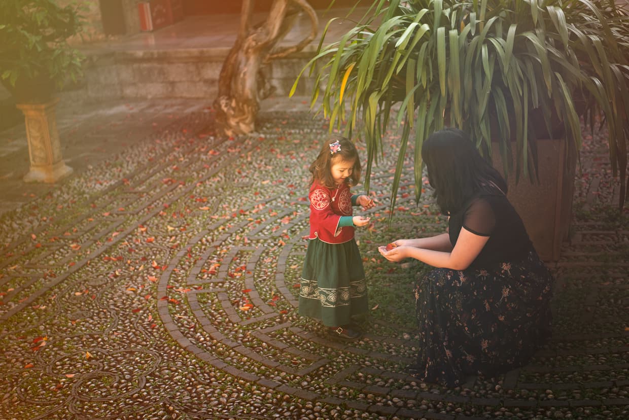 Mother and daughter gathering leaves in a Chinese palace courtyard.