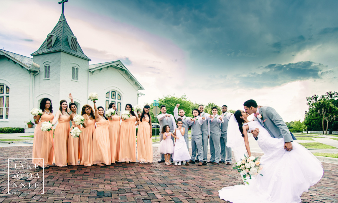 Bride and groom kissing on the brick road in front of the White Chapel in Palm Harbor, Florida.