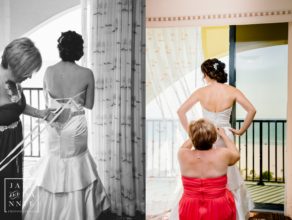 Mother of the bride helps with the wedding dress near the window at the beach