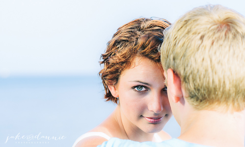 Susie looks over Trevor's shoulder and smiles near the ocean in Fort DeSoto Florida