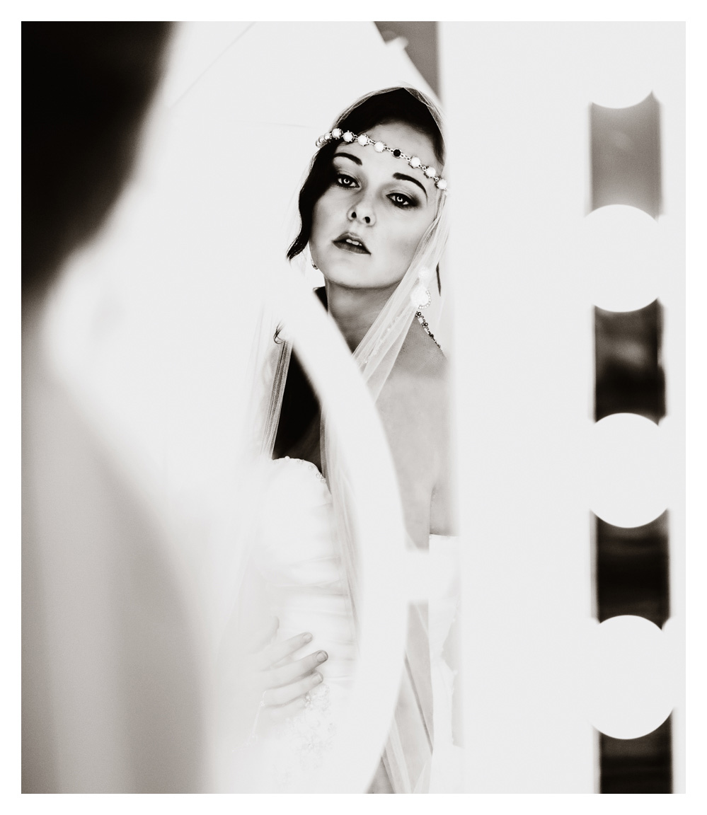 A bride getting ready in front of the mirror. Black and white.