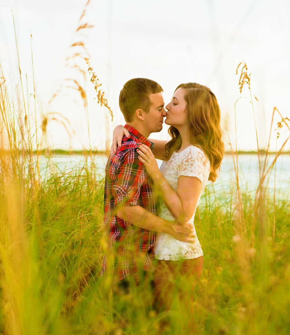 Couple kissing, hidden by the tall grass near the ocean