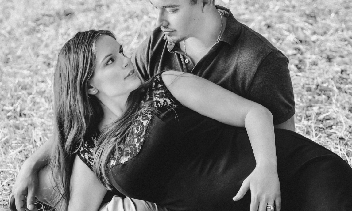 Couple rests in the grass during maternity photo session