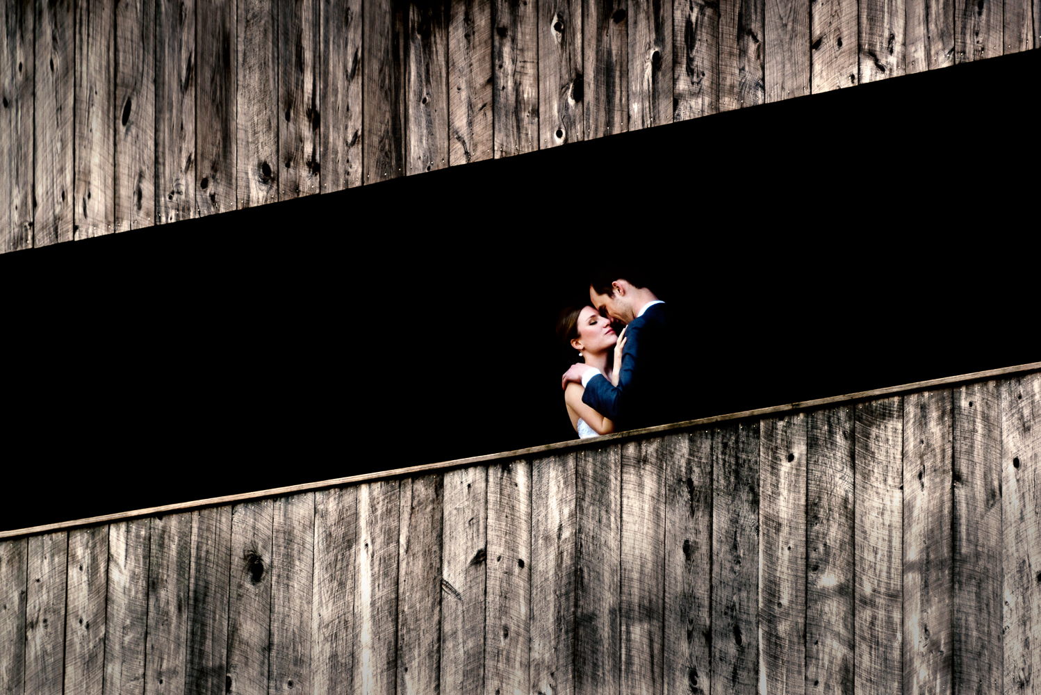 A bride and groom embrace on a covered bridge in jackson, New Hampshire