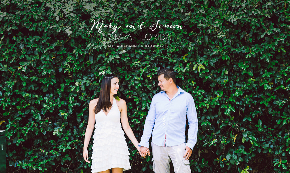 Couple holding hands in front of leafy bushes