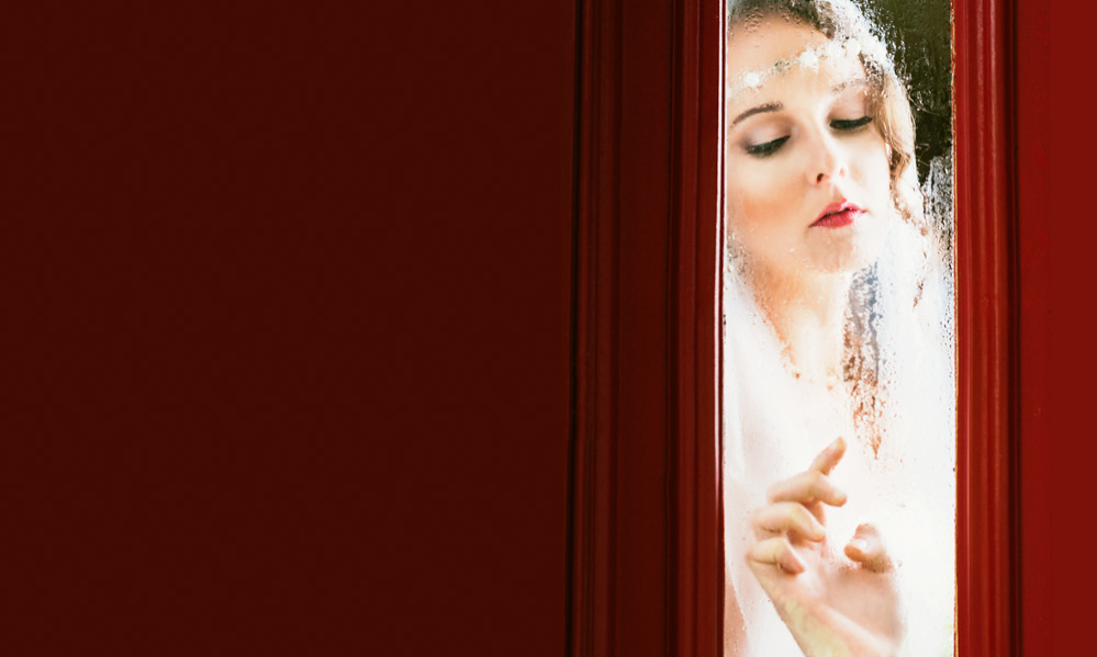 Bride in white looking out window