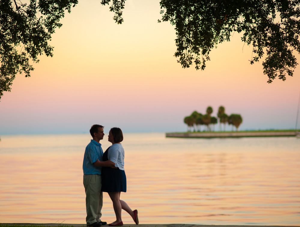 Couple embraces during engagement session near St Petersburg harbor at sunset