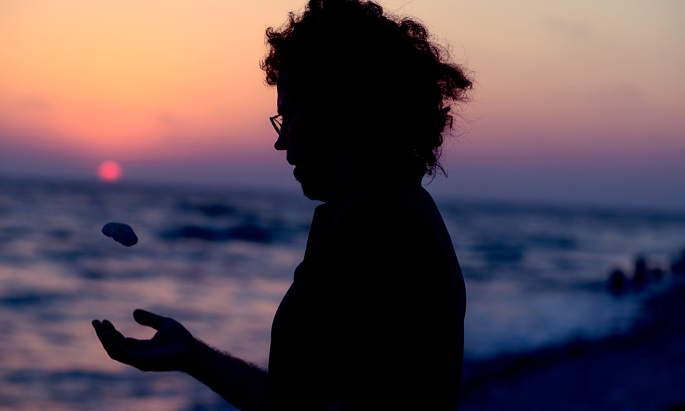 Silhouetted Jake tosses a rock during a florida sunset in this portrait photograph