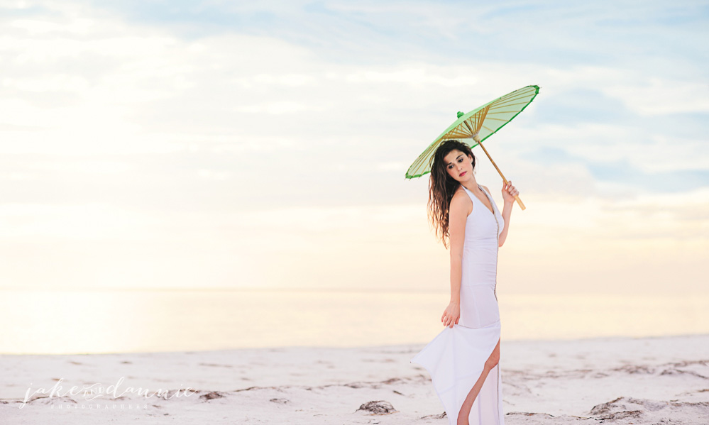Model Allison walks on beach in white dress with green umbrella