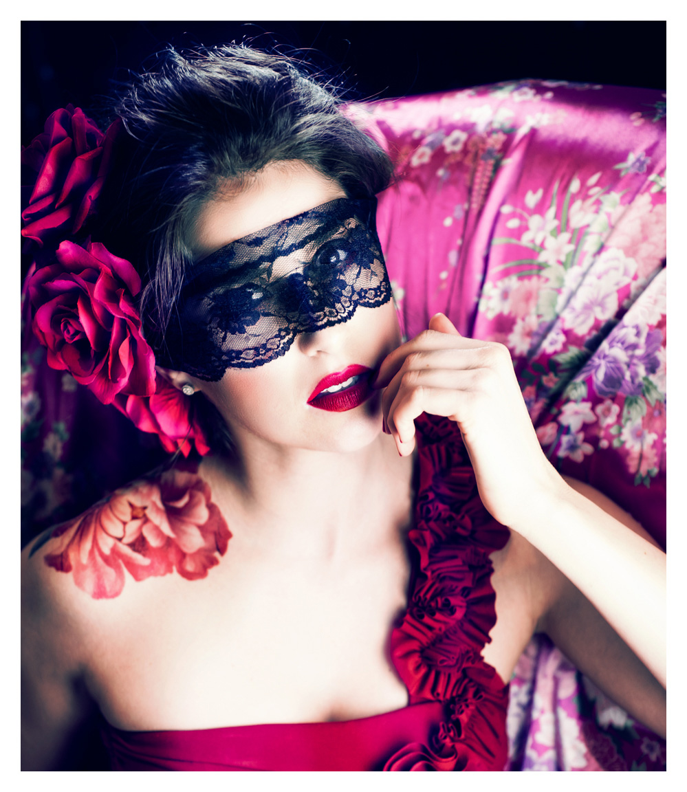 beautiful model in black mask poses for halloween fashion shoot wearing red dress