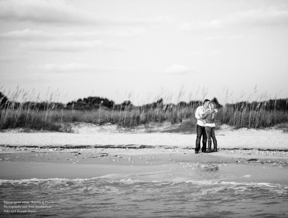 Future bride and groom kissing near the water in engagement photo